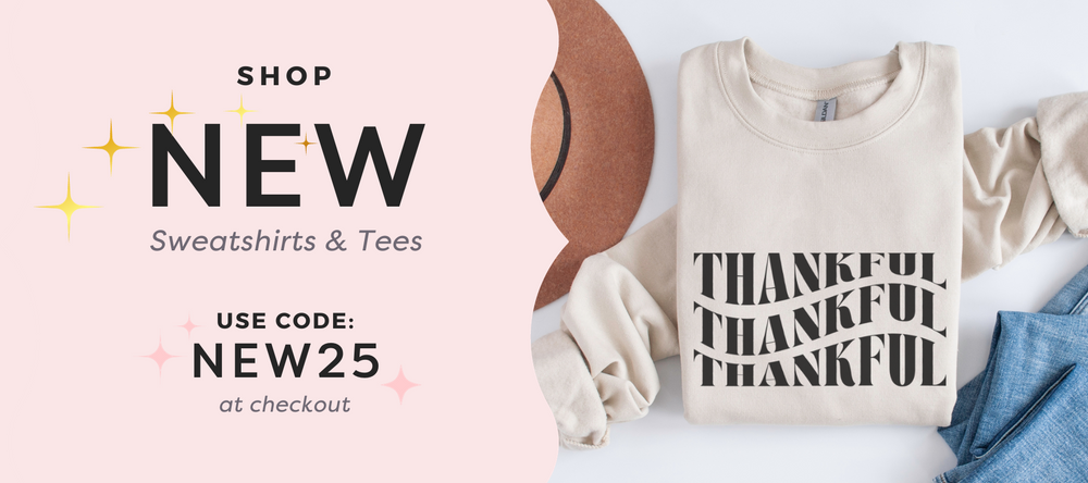 Home slide that reads “shop new sweatshirts & tees, use code new25 at checkout” with a light pink background and an image of thankful sweatshirt in sand color.